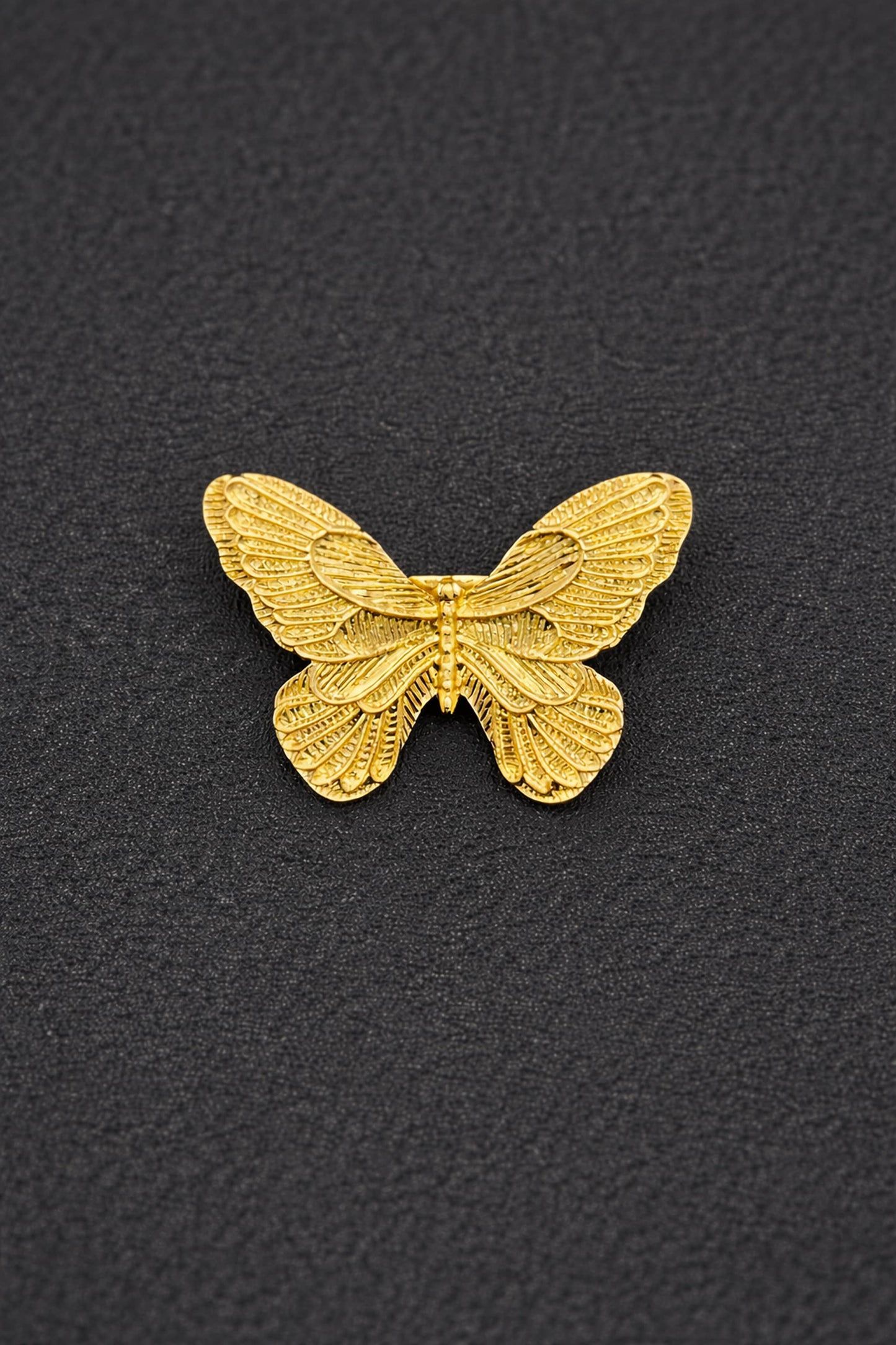 Gold butterfly-shaped object on a black textured background