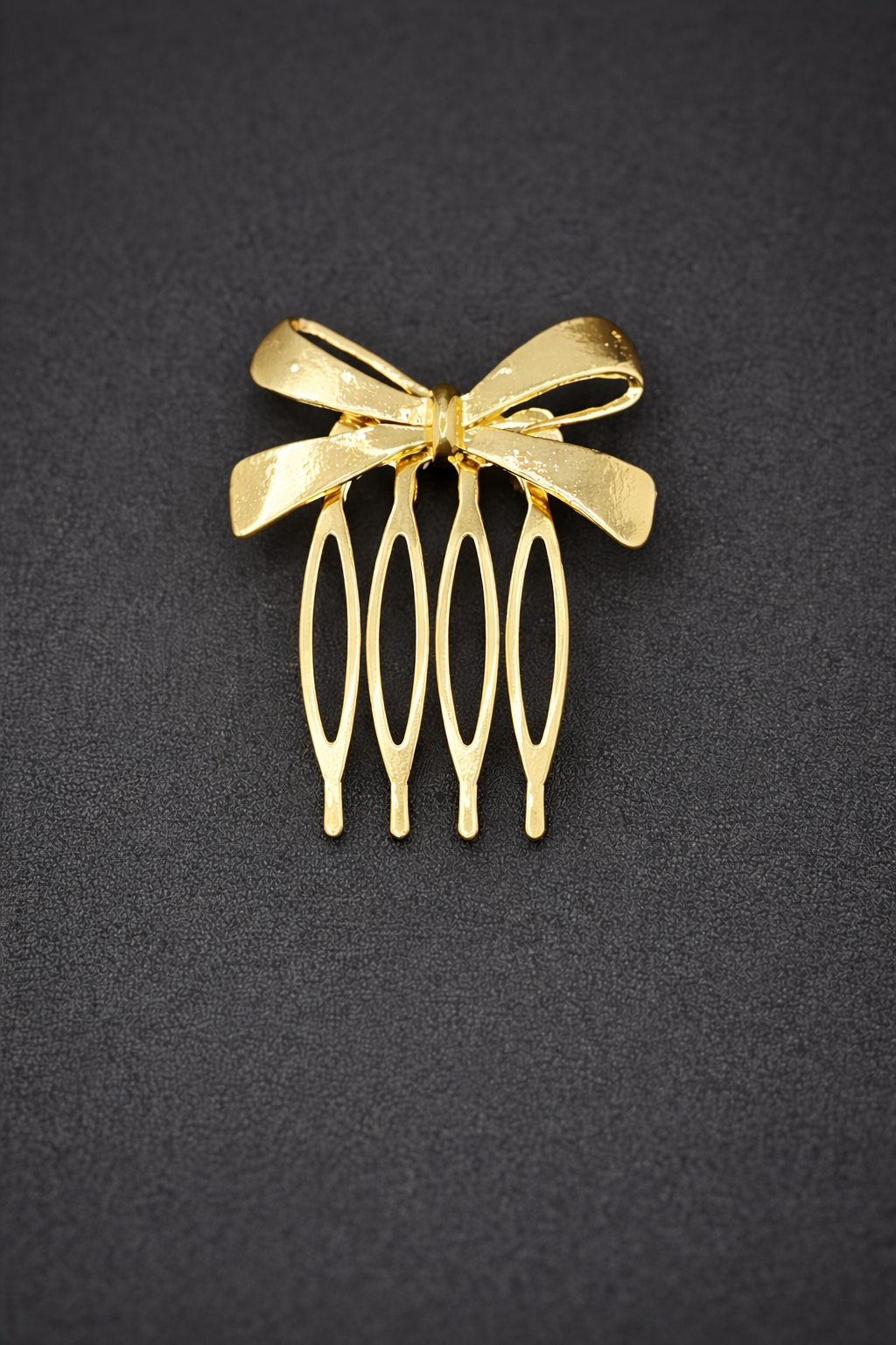 Gold hair comb with bow design on a black background