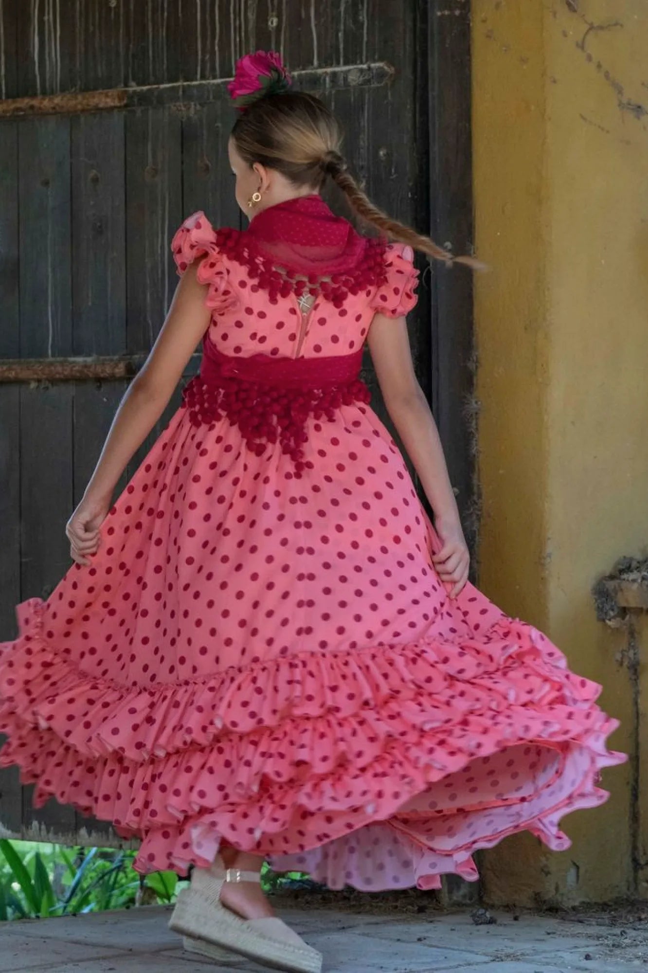 Woman in a pink dress with red polka dots walking outdoors.