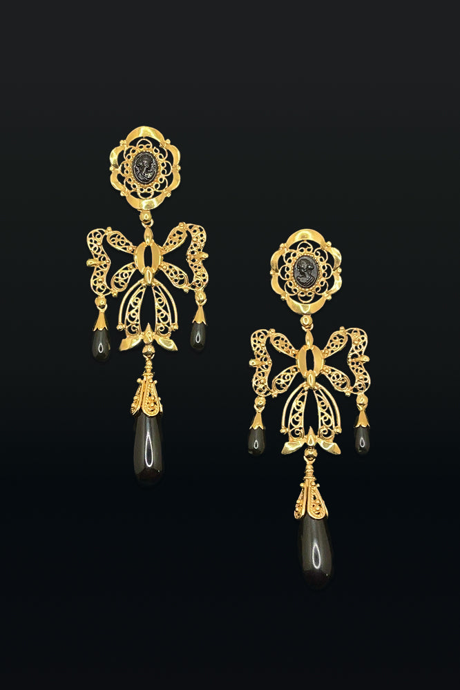 Gold earrings with black stones on a black background