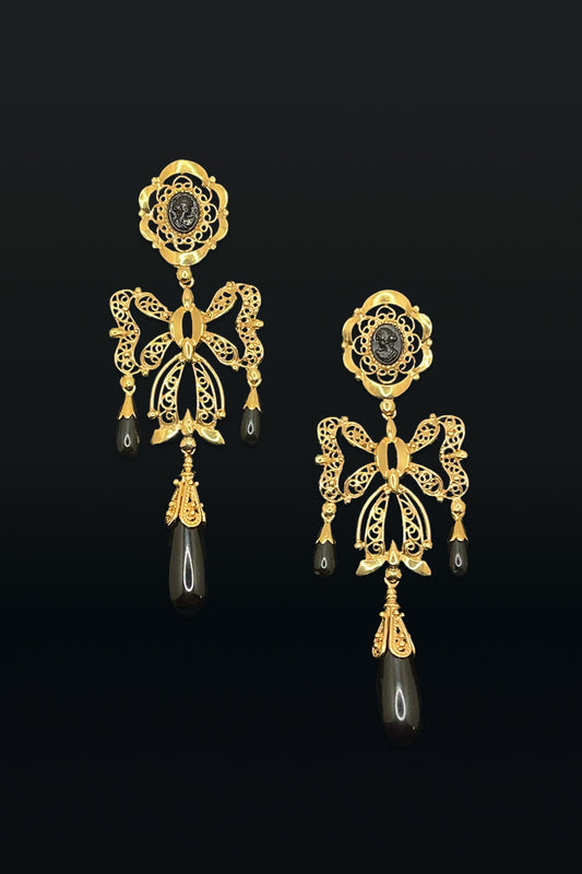 Gold earrings with black stones on a black background