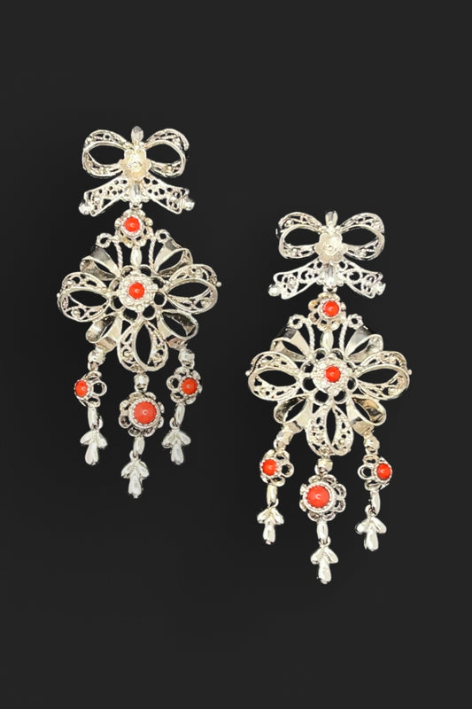 Pair of silver earrings with red gemstones on a black background