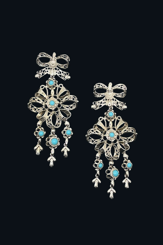 Pair of silver earrings with turquoise stones on a black background