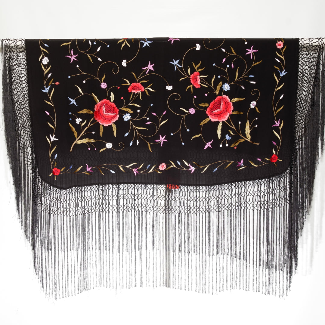 Black fabric with floral embroidery and fringe on a white background