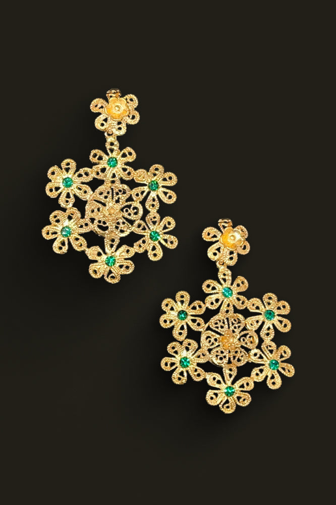 Gold earrings with green gemstones on a black background