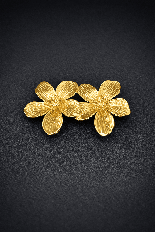 Gold floral earrings on a black background