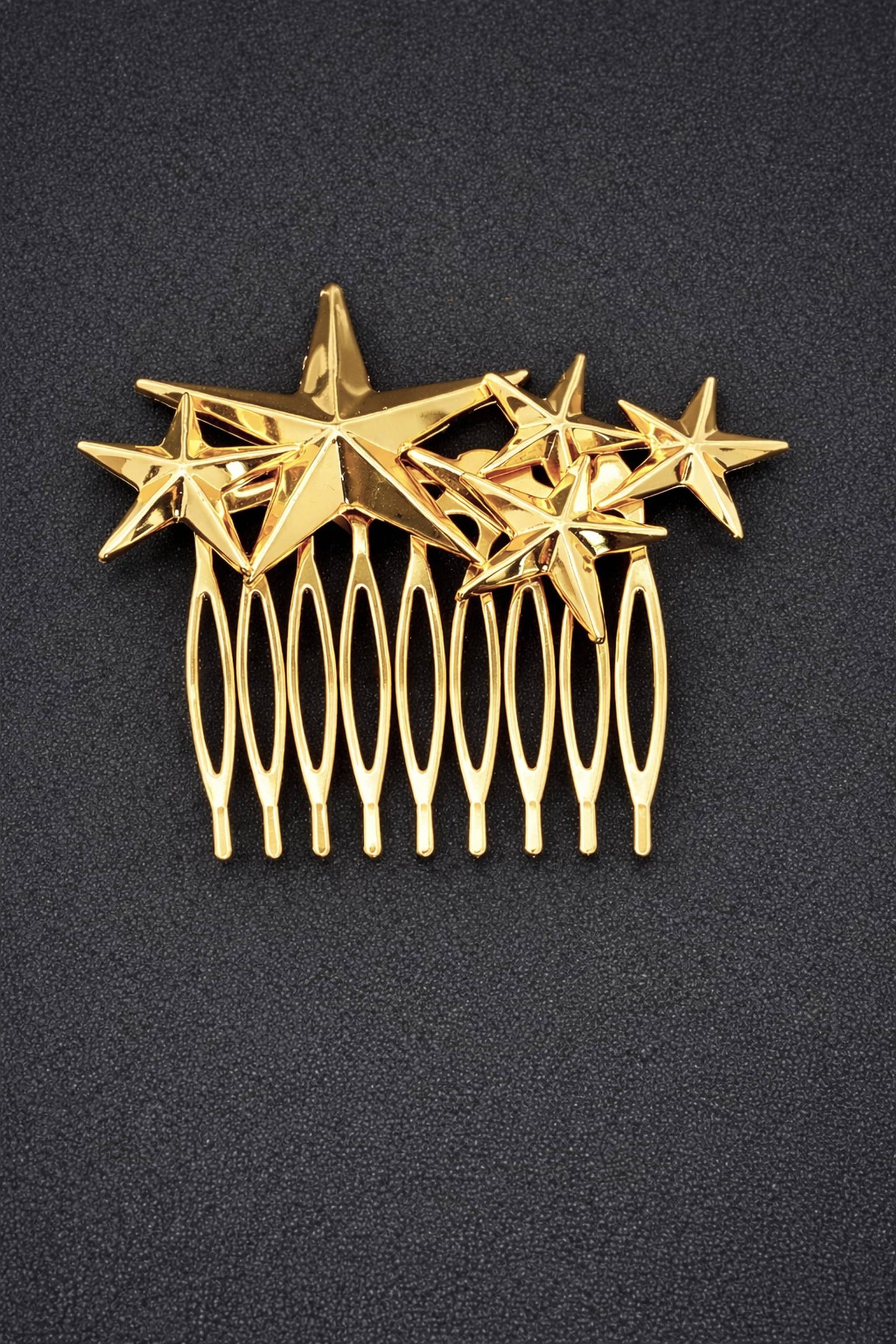 Gold hair comb with star designs on a black background