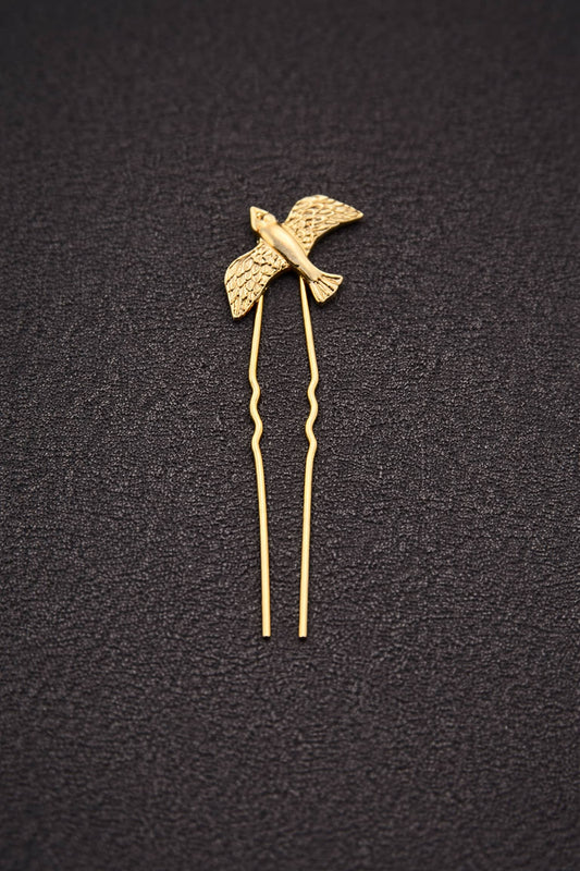 Gold bird-shaped hairpin on a black textured background