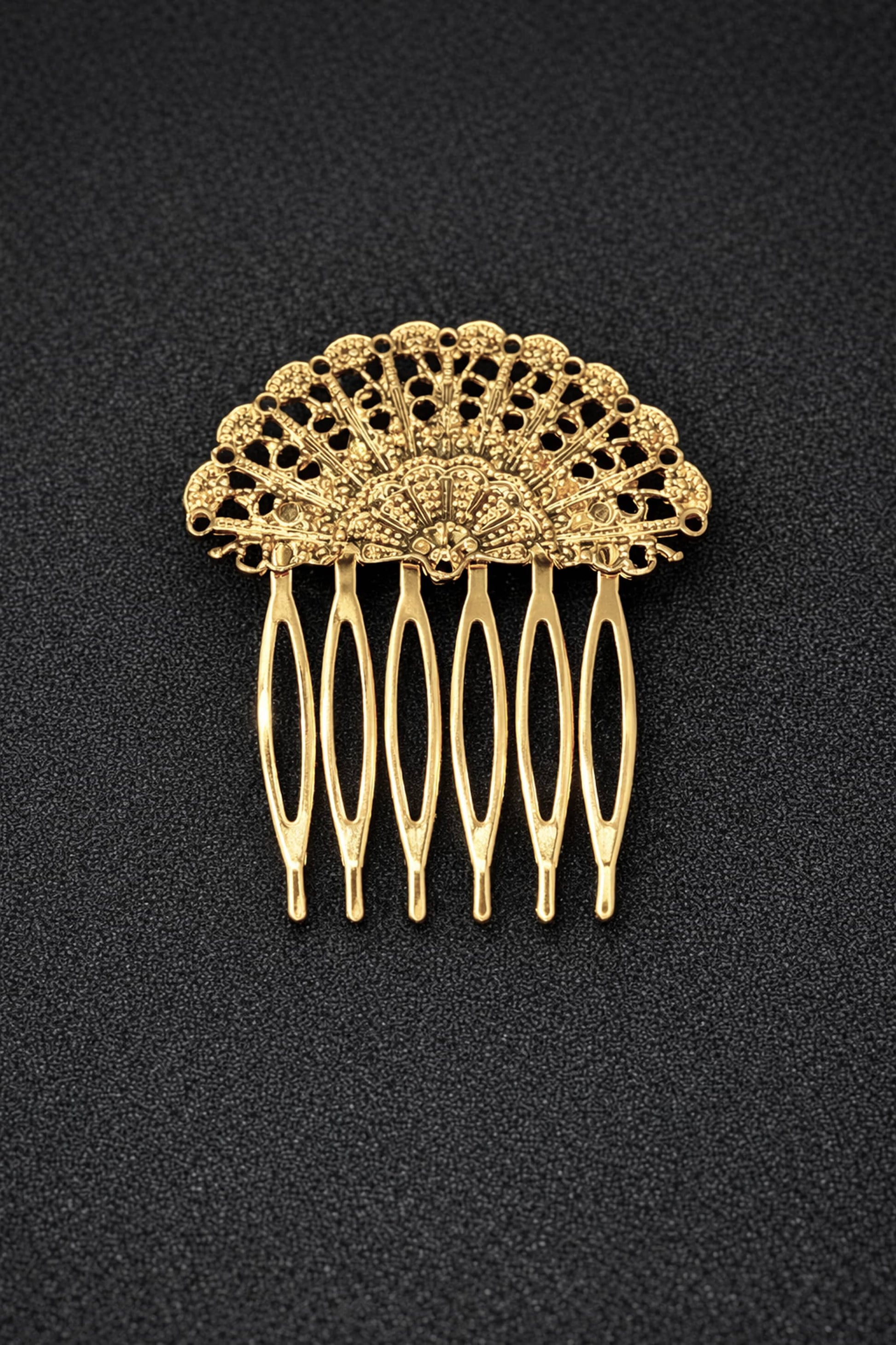 Gold hair comb with intricate design on a black background