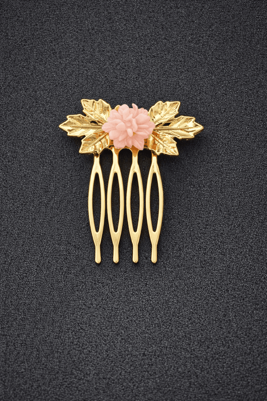 Gold hair comb with pink floral center on a black background