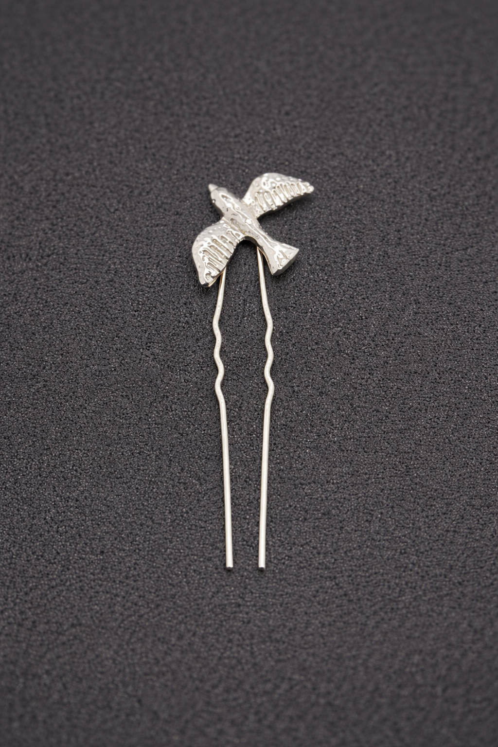 Silver bird-shaped hairpin on a dark textured background