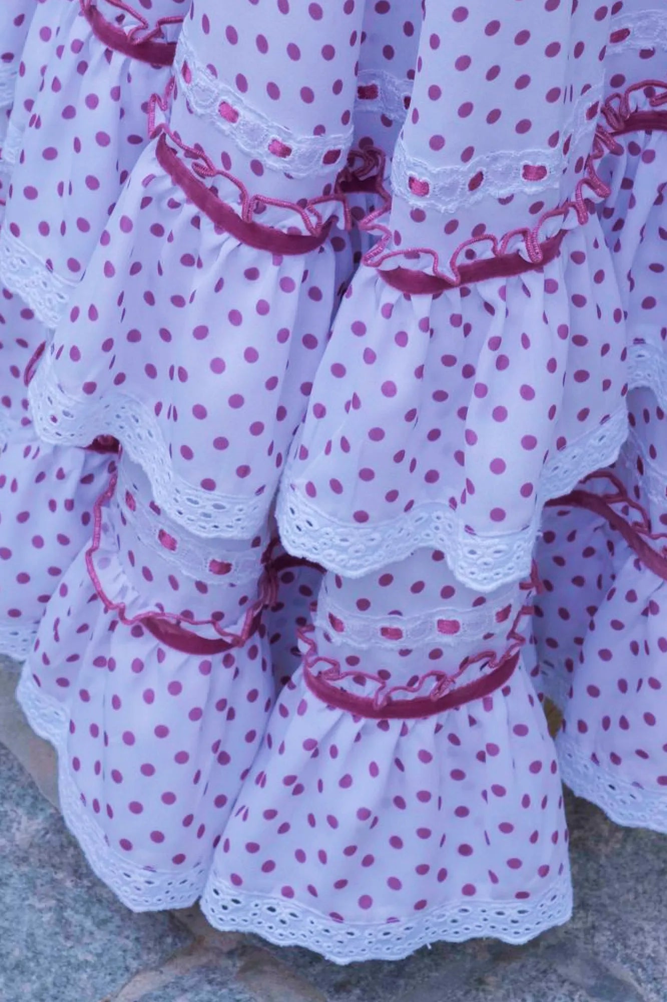 Close-up of a polka dot dress with ruffled layers on a textured surface.